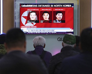 In this May 3, 2018 photo, people watch a TV news report screen showing portraits of three Americans, Kim Dong Chul, left, Tony Kim and Kim Hak Song, right, detained in the North Korea, at the Seoul Railway Station in Seoul, South Korea President Donald Trump says Secretary of State Mike Pompeo is on his way back from North Korea with three American detainees, saying they “seem to be in good health.” 