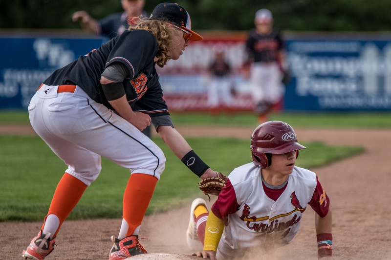 THE VINDICATOR | DIANNA OATRIDGEÊ Cardinal Mooney's Ethan Shaw avoids a pick off attempt by Howland's Dylan Keller during their Division II Sectional Final match-up at Cene Park on Wednesday. The Cardinals won the game 11-2.