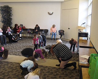 Neighbors | Zack Shively.Some of the songs sang or played at the "Gotta Move Story TIme" were classic children's songs, while others focused on specific tasks. Pictured, librarain Mallory Wiand played a song that asked the children to touch two body parts together, such as their nose and their knee, as they worked on their flexibility.