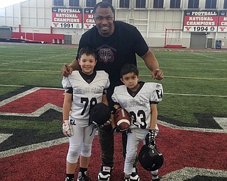 Neighbors | Submitted.Tim Johnson, former Youngstown State University Penguin, NFL linebacker for the Oakland Raiders and the Baltimore Ravens and creator and CEO of HIP is pictured with Holy Family students Greggory Hann and Osiron Talbott.