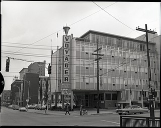 89.119 B3F157 Negative of the Voyager Motor Inn at the intersection of Market Street and Front Street in downtown Youngstown. Multiple directional signs are present on the telephone poles on either side of the corner. The Tod Hotel sits on the left side of the Voyager. The railing for the Market Street Bridge is visible in the bottom right corner. Taken July 1965. Archives, original negative is 4" x 5" black and white. Digital image is 800 dpi RGB.
