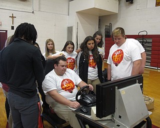 Neighbors | Zack Shively.The agencies in Cardinal Mooney's gym for their Yes Fest ranged from animal shelters to nursing homes to Mill Creek MetroParks. Pictured, the students gathered around to watch their friend use the Highway State Patrol's distracted driving simulator, where the student attempted to drive and send a text message at the same time.