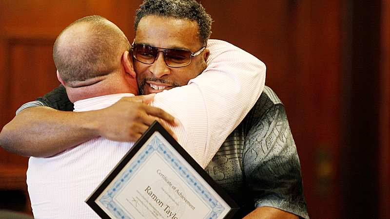 Ramon Taylor, right, hugs his mentor, Chris Derr, at the Honor Court graduation in Mahoning County Common Pleas Court on Tuesday. Taylor completed the program and had a pending criminal case against him dismissed as a result. 