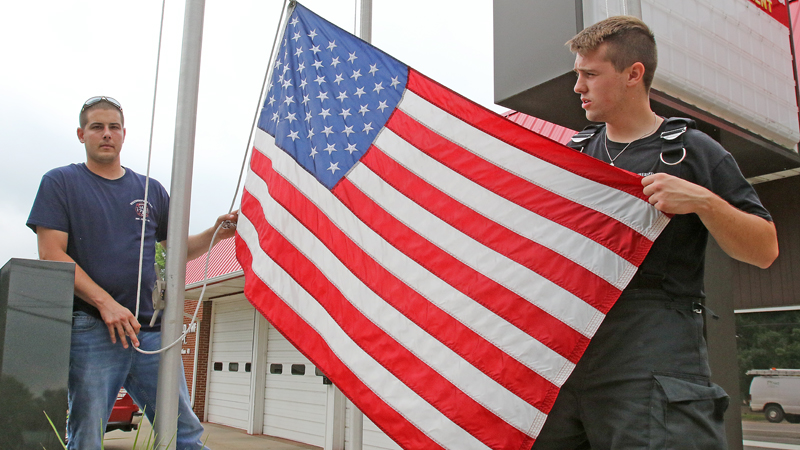 Weathersfield Fire Department Lt. Jeff Tucker, left, and Firefighter Andrew Garris carefully handle the American Flag at the fire station. The Mineral Ridge Flag Day Festival runs Thursday to Sunday.  