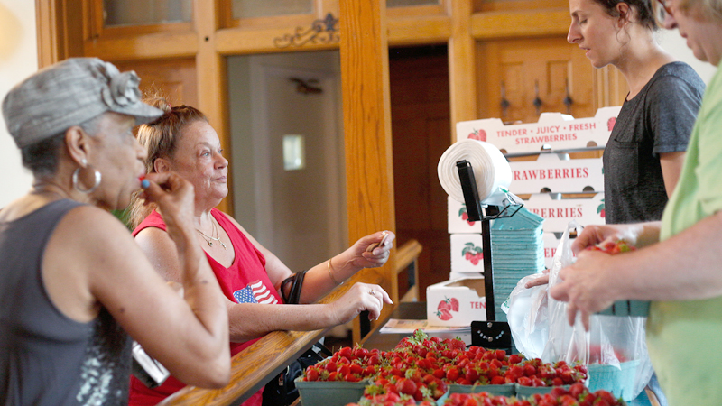 Delores Franklin, front left, and Debbie Maderitz buy strawberries from Janelle McHugh, back right, and Barb Yoder of Huffman Fruit Farm during the Youngstown Farmers Market at the B&O Station in downtown Youngstown on Wednesday. 