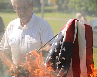 Bob Kirchner of American Legion Post 301 holds a flag in the flames during Austintown’s flag-burning ceremony Thursday in the Veterans’ Memorial Park.