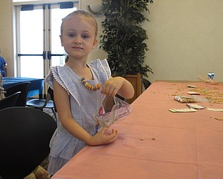 Neighbors | Zack Shively.The Austintown library's doughnut-themed program featured two activities using cereal, since the cereal used resembled the shape of doughnuts. One of these activities had the children at the event gather cereal to use as bird food. Pictured, Aubrey Cavalier collected the cereal in a small bag.