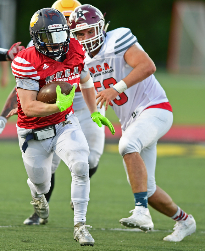 CANFIELD, OHIO - JUNE 14, 2018: Trumbull County's Alex Clark runs the ball away from Mahoning County's Steven Amstutz during the second half of the Jack Arvin All Star Football game, Thursday night at Canfield High School. DAVID DERMER | THE VINDICATOR