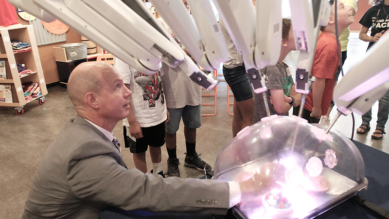 Ryan Ward of Intuitive Surgical Inc. shows off the robotic arms of the Da Vinci surgical system to day campers at OH WOW! The Roger & Gloria Jones Children’s Center for Science & Technology in downtown Youngstown.  On Monday, Ward adjusted a penny the campers magnified and inspected using the system, which is used in a variety of surgeries. 