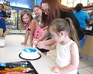 Neighbors | Zack Shively.Dairy Queen provided families with blank cake to decorate for their Father's Day event. The families could choose three different sized cakes. The families used airbrushes, sprinkles, gels and ribbons to decorate the treats. Pictured, the Bushling family decorated the cake using an icing pen.