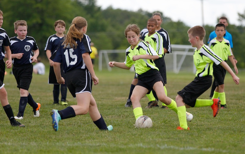 Gianna Franklin, center, a player on the 12U team sponsored by Backdraft, tries to keep control of the ball during a game against Glenwood Chevrolet Saturday in Austintown. The Austintown Junior Soccer League is celebrating its 40th anniversary this weekend.