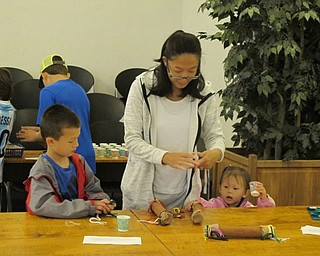 Neighbors | Jessica Harker .Eli Mains worked with his mother, Amy, and his younger sister, Emma, to make two rain sticks at the Austintown library on June 27.