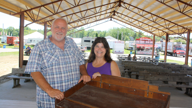Trumbull County Fair Board President Bud Rogers stands Monday with longtime fairgoer and volunteer Merrily Carroll in the new pavilion near the new restrooms at the Trumbull County Fairgrounds in  Bazetta Township. The pavilion, which has 24 benches and 16 picnic tables under the shade, will make a good place to get out of the sun, eat and enjoy musical performances at the Historical Stage on which Rogers and Carroll are standing. The fair opens today.