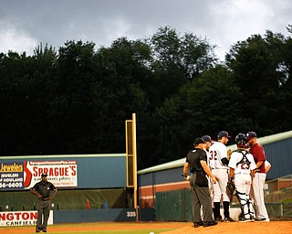 The Scrappers infield huddle on the mound as storm clouds roll in during the fourth inning of Tuesday night's game.