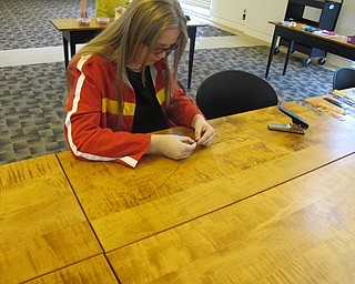Neighbors | Natalie Wright.A participant patiently tied strings to the guitar pick she made from a plastic strip. She said that she planned on continuing to work on the pick later at home to make a more complex design.