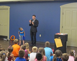 Neighbors | Natalie Wright.A young volunteer from the audience helped David Anthony perform a feat of magic involving the appearance of a yellow scarf tied between blue ones while inside of the volunteer's pocket. Only the blue scarves were present when they were placed into the pocket.