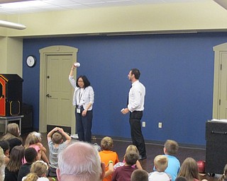 Neighbors | Natalie Wright.Boardman librarian Mary Yee aided magician David Anthony in a trick at the Boardman library on July 16. Everyone thought that water previously poured into the cup would spill onto Yee's head after she tipped the glass over, but it had magically disappeared.
