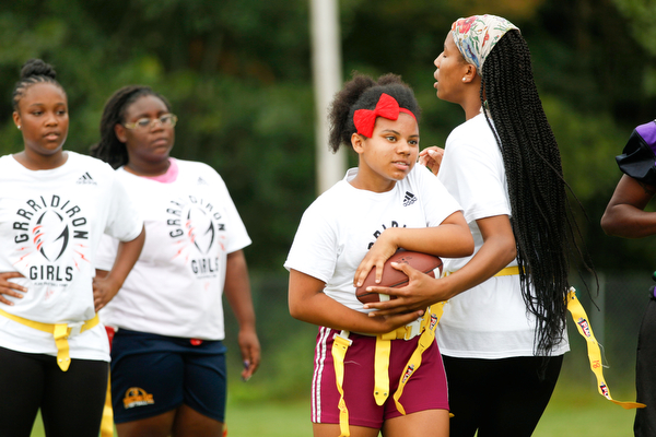 Donavan Gillison, 16, right, of Youngstown, hands the ball off to Laionia Williams, 13, of Youngstown, while Janay Shaw, 15, far left, and Calya Findley, 15, both of Youngstown, watch and wait for their turn at the Grrridiron Girls Flag Football Camp at Glacier Field in Struthers on Tuesday. EMILY MATTHEWS | THE VINDICATOR