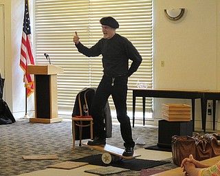 Neighbors | Jessica Harker.Michael Baldridge balanced on a board placed on a roll of cardboard to showcase the strength of certain types of paper at the Paper Magic event July 24 at the Austintown library.