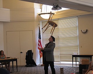 Neighbors | Jessica Harker.Michael Baldridge balanced a chair on his head during the July 24 Paper Magic event at the Austintown library.