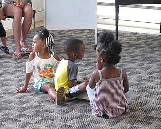 Neighbors | Jessica Harker.Kaeya Brown, Liam Beverly and Amaya Elliott all sat on the ground as the librarian read a book during the Baby Brilliant event July 3.