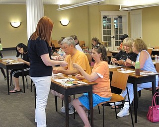 Neighbors | Jessica Harker .Missy Williams, adult programing librarian, walked table to table making sure everyone was keeping up with instructions on July 10 during the lava stone necklace making event at the Poland library.