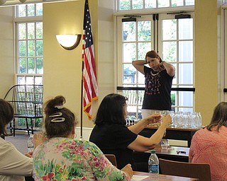 Neighbors | Jessica Harker .Librarian Missy Williams put on her example of the lava stone necklace to show participants at the Poland library July 10.