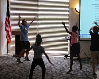 Neighbors | Jessica Harker.Librarian Allison Graf leads children in a set of warm up jumping jacks at the Gotta Move 2.0 story time on July 27.