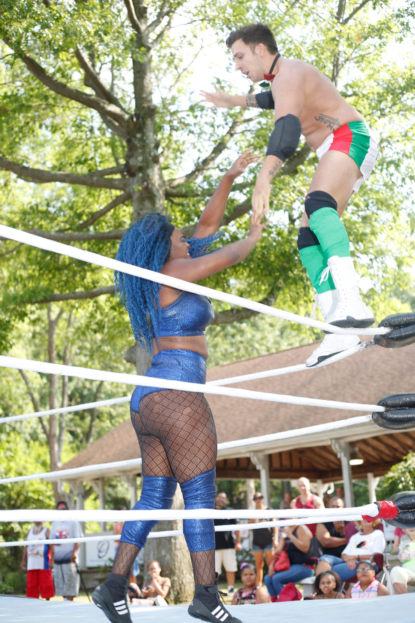 Wrestler Mambo Italiano,right, stands on the ropes above his opponent Joseline Navarro in a headlock at the Latino Heritage Festival in Campbell on Saturday. EMILY MATTHEWS | THE VINDICATOR