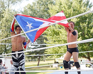 Wrestlers Marc-Anthony Alejandro and Calvin Couture hold up a Puerto Rican flag after their match against Cree Fudo and Dan Hooven at the Latino Heritage Festival in Campbell on Saturday. EMILY MATTHEWS | THE VINDICATOR