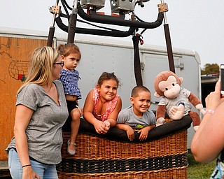 From Left, Amanda Vega, of Boardman, Veronica Vega, 2, Aaliyah Plourde, 5, of Brooklyn, and Damian Vega, 4, of Boardman smile in a hot air balloon basket as Esther Plourde, of Brooklyn, takes their photo at the Hot air balloon festival at Mastropietro Winery on Sunday..