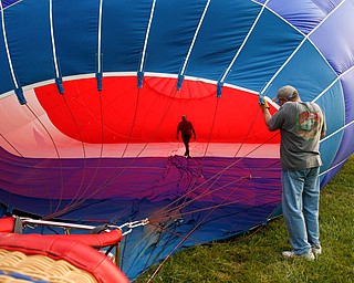 Rick Kohut, a hot air balloon pilot, walks inside a hot air balloon while Chuck Evans, of Austintown, holds it up while it inflates at the Hot air balloon festival at Mastropietro Winery on Sunday..