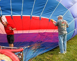 Rick Kohut, a hot air balloon pilot, walks out of a hot air balloon while Chuck Evans, of Austintown, holds it up while it inflates at the Hot air balloon festival at Mastropietro Winery on Sunday..