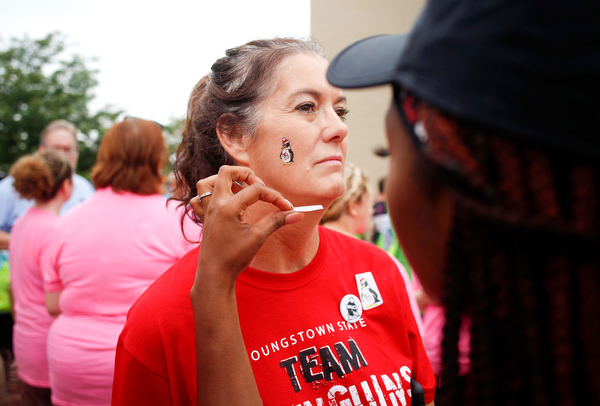 Molly Roche, a member of the YSU nursing faculty, gets a penguin tattoo on her face from Shauntiaonia Johnson, a senior studying nursing at YSU, before the start of Panerathon outside of Covelli Centre on Sunday. .EMILY MATTHEWS | THE VINDICATOR