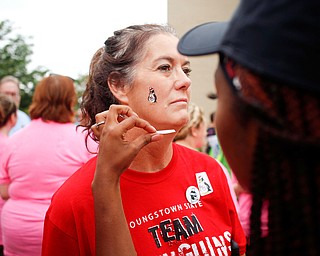 Molly Roche, a member of the YSU nursing faculty, gets a penguin tattoo on her face from Shauntiaonia Johnson, a senior studying nursing at YSU, before the start of Panerathon outside of Covelli Centre on Sunday. .EMILY MATTHEWS | THE VINDICATOR