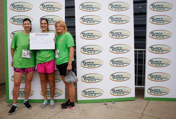 From left, Dawn Johnson, of Boardman, Debbie Rowder, of Austintown, and Lisa Galgozy, of Boardman, pose for a photo before the start of Panerathon outside of Covelli Centre on Sunday. Their sign is for Rowder's friend Tammy, who had a double mastectomy due to breast cancer..EMILY MATTHEWS | THE VINDICATOR
