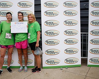 From left, Dawn Johnson, of Boardman, Debbie Rowder, of Austintown, and Lisa Galgozy, of Boardman, pose for a photo before the start of Panerathon outside of Covelli Centre on Sunday. Their sign is for Rowder's friend Tammy, who had a double mastectomy due to breast cancer..EMILY MATTHEWS | THE VINDICATOR