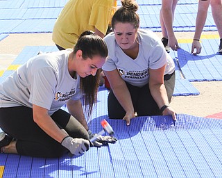  ROBERT K.YOSAY  | THE VINDICATOR..Darya (ok) Snoznik  and Madison Connelly  fix a seam on the DEK hockey ring...Mill Creek ParkÕs old ice skating rink is getting a blue makeover courtesy of a team that wears black and gold..On Tuesday morning, volunteers from Mill Creek MetroParks, Home Savings and Loan, the Youngstown Phantoms and The Pittsburgh Penguins Foundation were laying down blue tiles for the ParkÕs new dek hockey rink