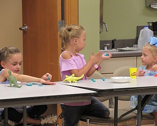 Neighbors | Jessica Harker.Children used play dough to make 'fossils' by pressing their plastic dinosaurs into it at the August 16 Sprout Club event at the Fellows Riverside Garden.