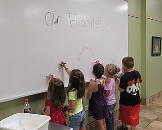 Neighbors | Jessica Harker.Children drew outlines of the shapes their dinosaurs made in the play dough August 16 at the Sprout Club event.