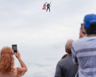 People watch and take photos as Jimmy Drummond, of Youngstown, skydives at the Austintown Patriot Day ceremony outside of Quaker Steak and Lube in Austintown on Thursday. EMILY MATTHEWS | THE VINDICATOR