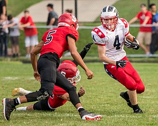 DIANNA OATRIDGE | THE VINDICATOR  Niles' Trent Johnson (4) eludes Struthers' Tyrese Hawkins (5) and  Robery Tomko (34) during their game in Struthers on Friday.