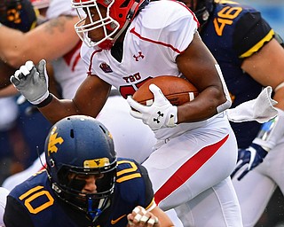 MORGANTOWN, WEST VIRGINIA - SEPTEMBER 8, 2018: Youngstown State's Tevin McCaster runs the ball away from West Virginia's Dylan Tonkery and Reese Donahue during the first half of their game, Saturday night. DAVID DERMER | THE VINDICATOR