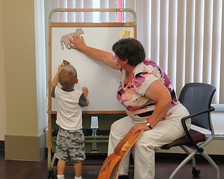 Neighbors | Jessica Harker.Childrens librarian Karen Saunders helped Collin Chasko place the magnetic cut outs of a cow and calf on the magnetic board during her telling of the story "Moo Moo Brown Cow".