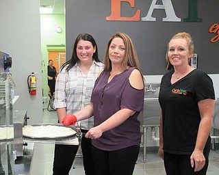 Neighbors | Jessica Harker.Employees Morgan Erownoie and April johnson stand around Ammie Perez (center) the owner of the new Carbless Craze Cafe on Sept. 7 as she bakes a glutton free pizza.