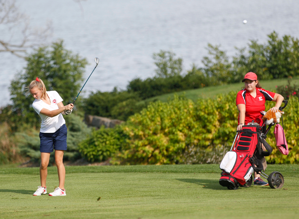 Cammille Hagan, left, with the Austintown Fitch girls golf team, hits her ball while Stephanie Novah, of Columbiana, watches during the Christine Terlesky Lake Club Girls High School Golf Invitational on Sunday. EMILY MATTHEWS | THE VINDICATOR