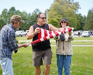 Angelo Nuzzo, center, the events coordinator of Ohio Flags of Honor, demonstrates how to roll and bag a flag with the help of Madeline and David Dunchak, of Boardman, after the closing ceremonies for the traveling memorial on Sunday. EMILY MATTHEWS | THE VINDICATOR