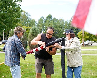 Angelo Nuzzo, center, the events coordinator of Ohio Flags of Honor, demonstrates how to roll and bag a flag with the help of Madeline and David Dunchak, of Boardman, after the closing ceremonies for the traveling memorial on Sunday. EMILY MATTHEWS | THE VINDICATOR