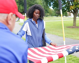 Shentel Wall, right, of Youngstown, and John Stun, of Hubbard, roll up one of the flags from the memorial after the closing ceremonies for the traveling memorial on Sunday. EMILY MATTHEWS | THE VINDICATOR