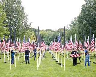 Volunteers help take down, roll, and bag the flags after the closing ceremonies for the traveling memorial on Sunday. EMILY MATTHEWS | THE VINDICATOR